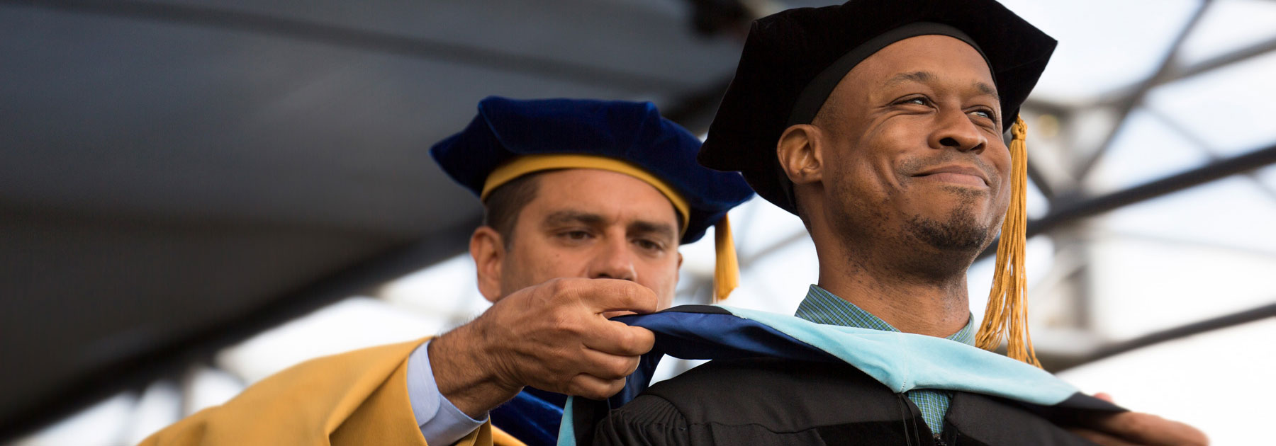 Faculty placing a sash on a graduate commemorating a diploma