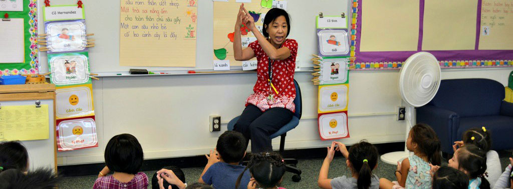 Teacher sitting down in front of a group of young students