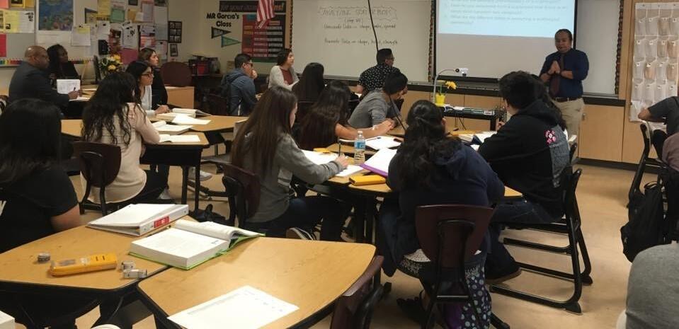 Group of students in classroom with an instructor at a projector screen